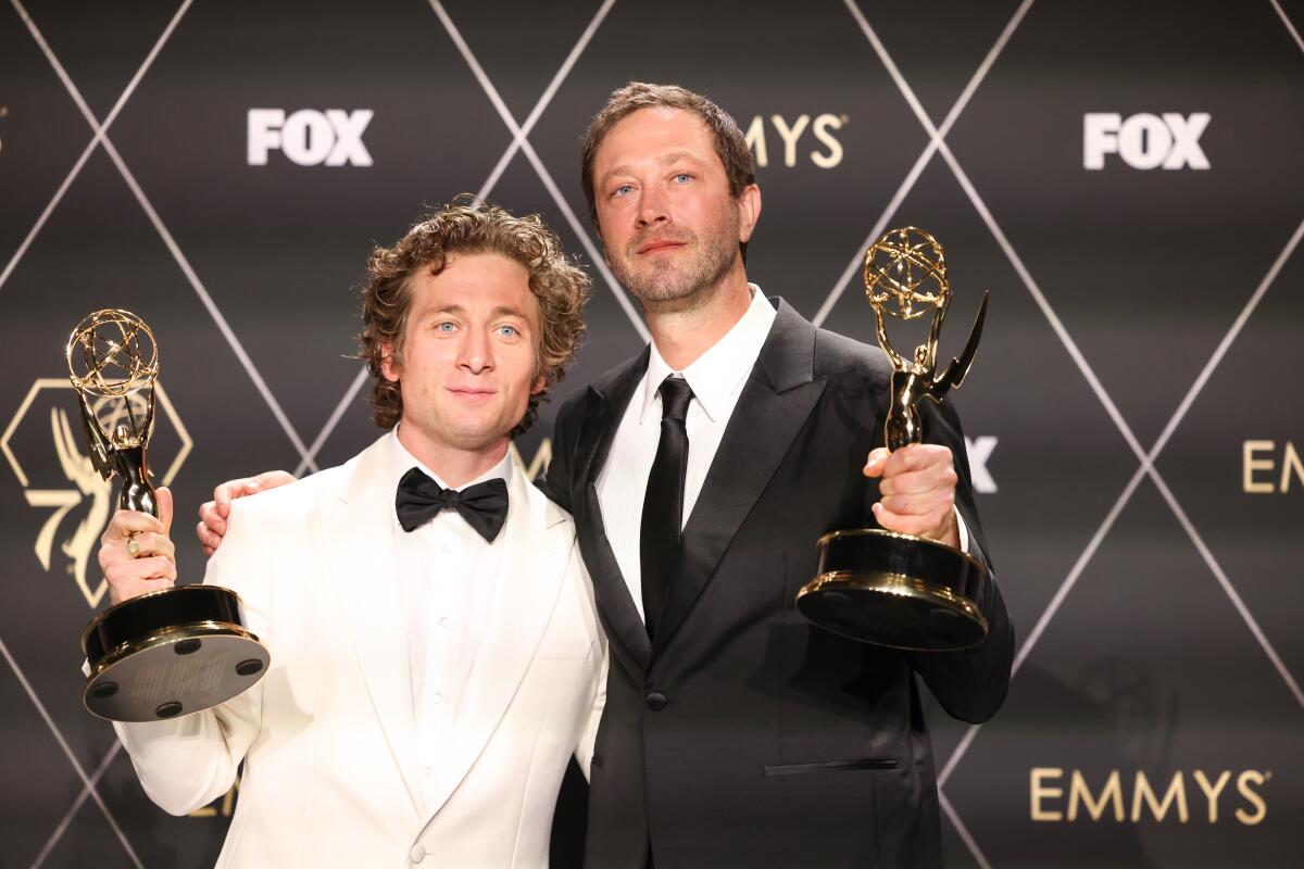 Two actors hold Emmy trophies.