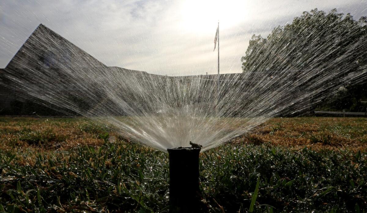 In this July 2014 photo, sprinklers water a lawn in Sacramento.