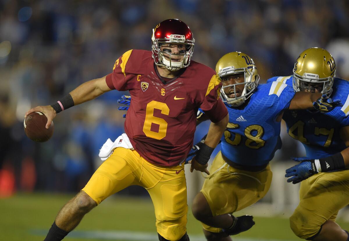 USC quarterback Cody Kessler (6) tries to escape UCLA's Deon Hollins (58) and Eddie Vanderdoes at the Rose Bowl on Saturday.