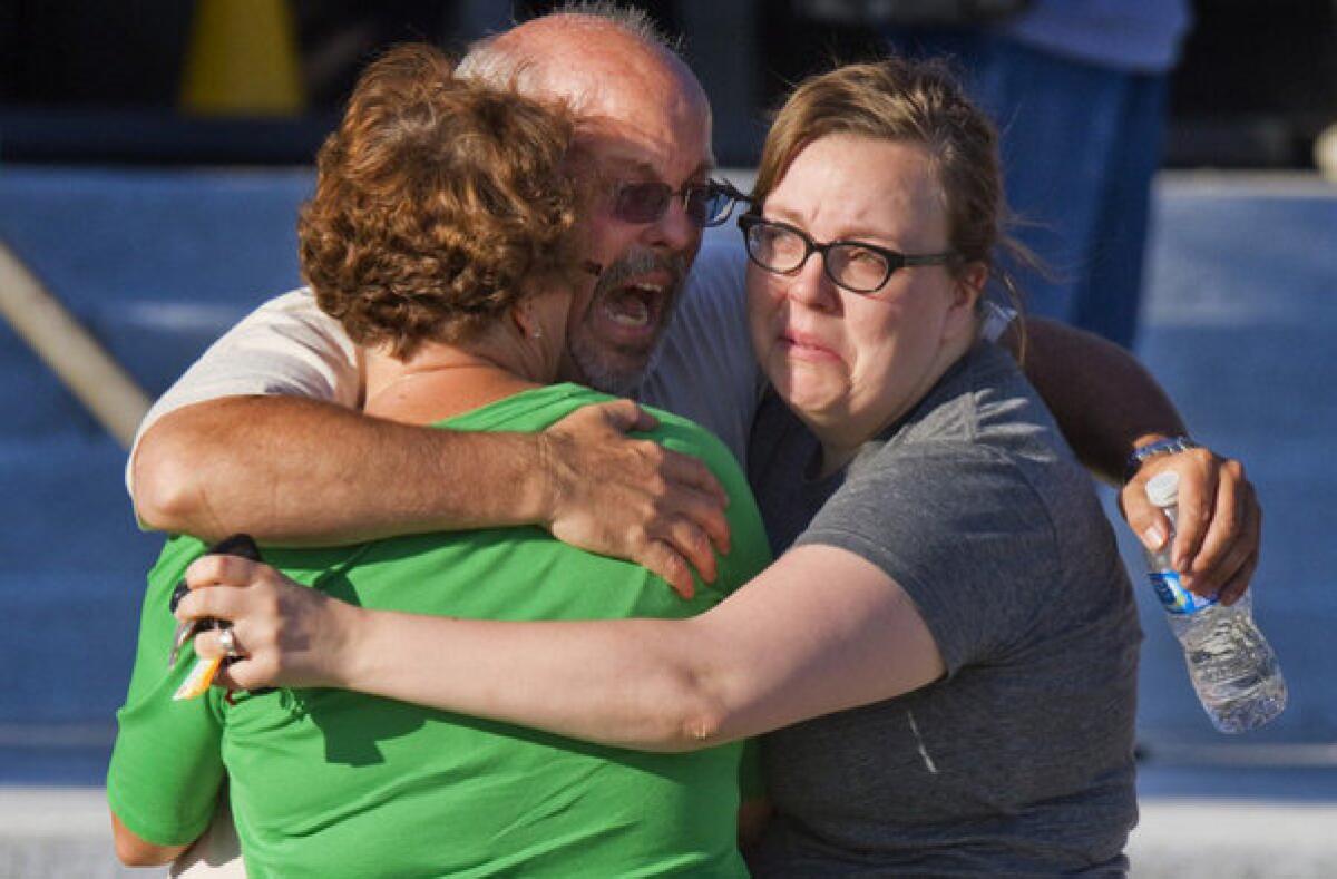 After the July shooting, Tom Sullivan, center, embraces family members outside Gateway High School where he had been searching for his son, Alex Sullivan, who celebrated his 27th birthday by going to see "The Dark Knight Rises" at a movie theater where a gunman opened fire, in Aurora, Colo.