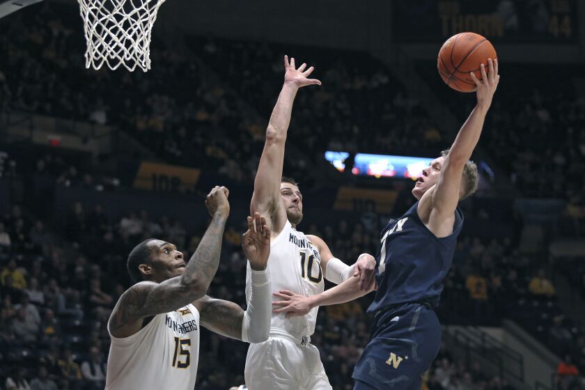 Navy guard Austin Benigni (1) shoots while defended by West Virginia forward Jimmy Bell Jr. (15) and guard Erik Stevenson (10) during the first half of an NCAA college basketball game in Morgantown, W.Va., Wednesday, Dec. 7, 2022. (AP Photo/Kathleen Batten)