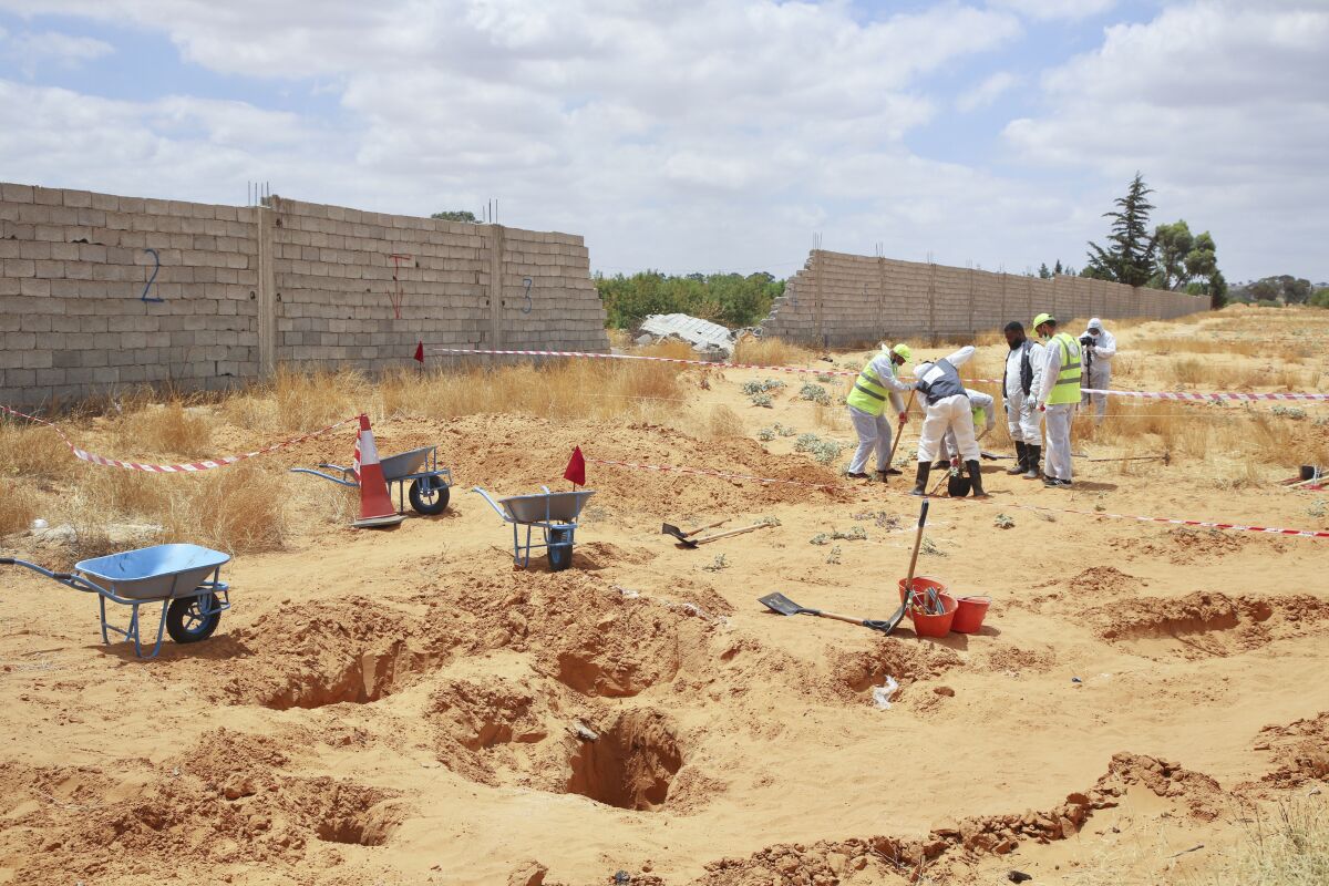 Libyan Ministry of justice employees dig out at a siyte of a suspected mass grave in the town of Tarhouna, Libya, Tuesday, June 23, 2020. The United Nations said that at least eight mass graves have been discovered, mostly in Tarhuna, a key western town that served as a main stronghold for Khalifa's east-based forces in their 14-month campaign to capture the capital, Tripoli. (AP Photo/Hazem Ahmed)