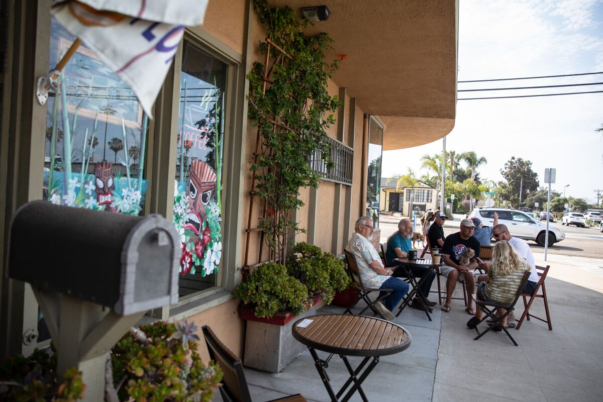 Customers talk and enjoy drinks outside Kona Hut Coffee House in Oceanside on Thursday.