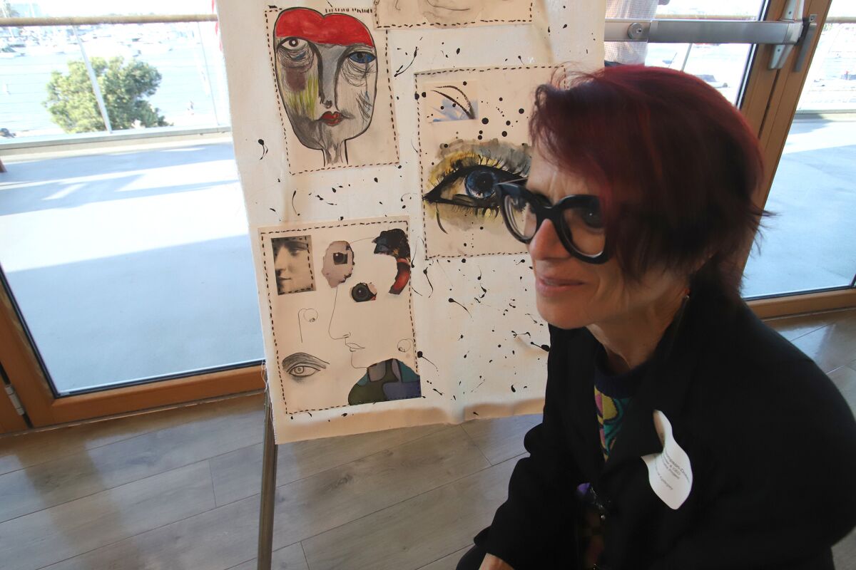 Dr. Julie Thompson-Dobkin, co-founder and CEO of Hidden Truths, seated next to her artwork, "Masks."