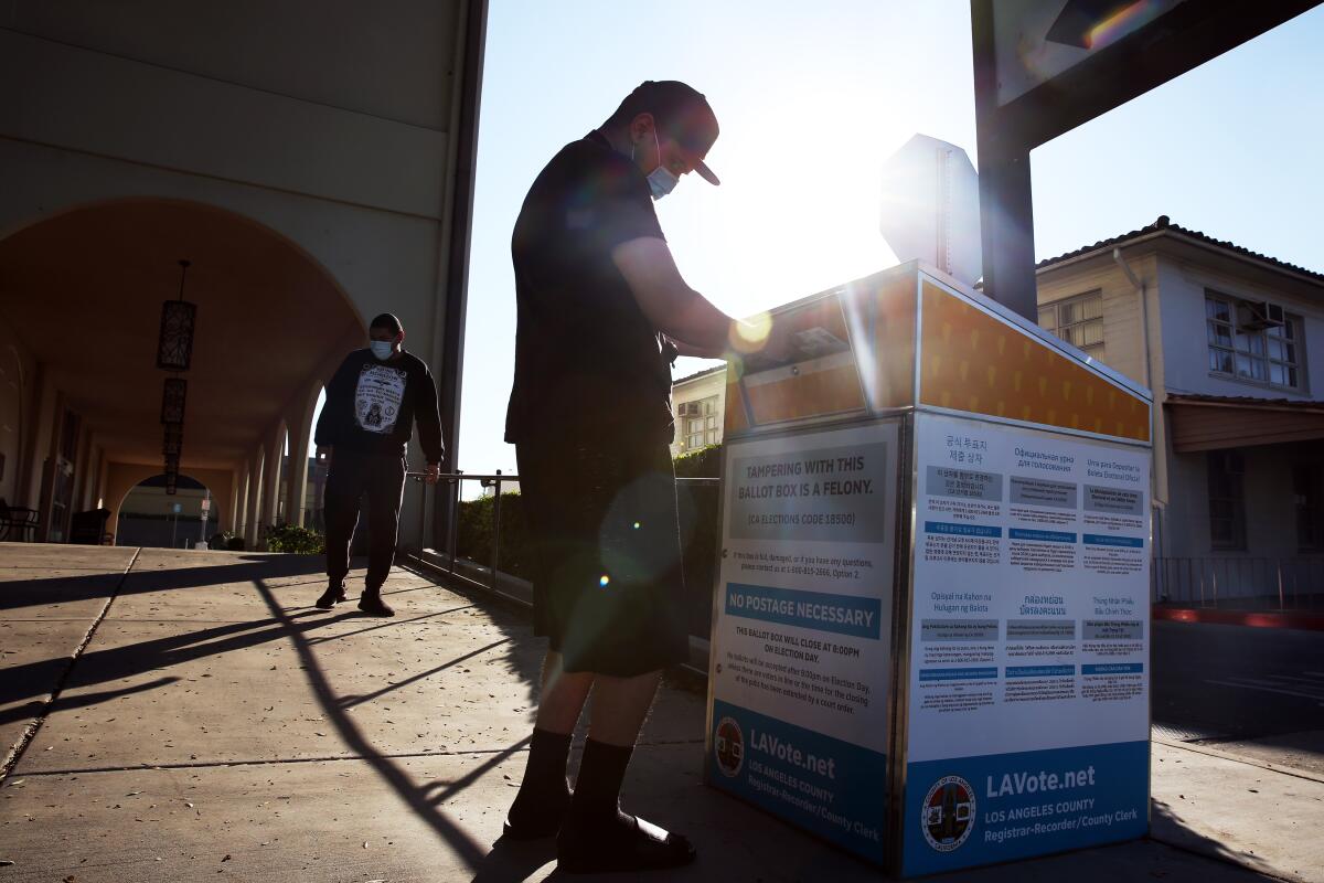 A man drops his ballot into an official ballot drop box