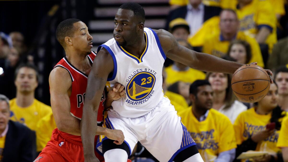 Golden State Warriors' Draymond Green is defended by Portland Trail Blazers' C.J. McCollum on May 11, 2016 in Oakland, Calif.