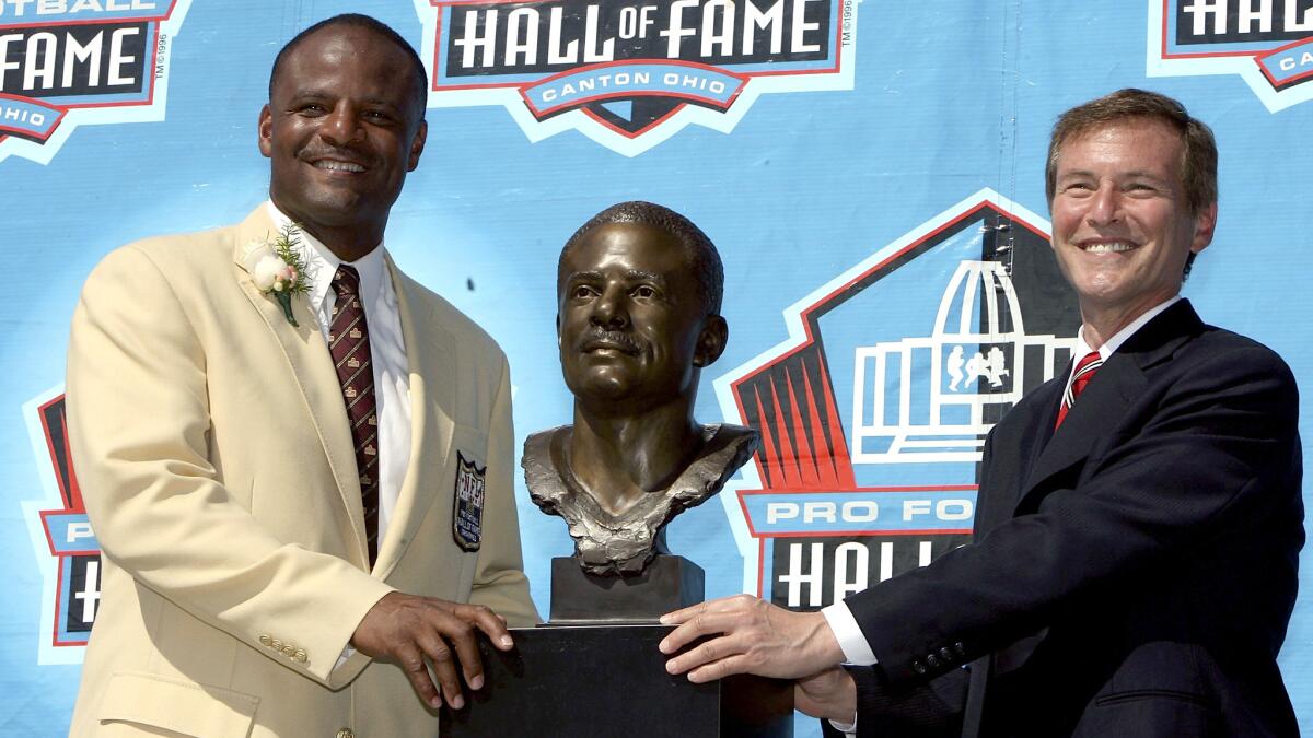 Warren Moon, left, poses with his bust and his presenter Leigh Steinberg after Moon's induction ceremony for the Pro Football Hall of Fame in 2006