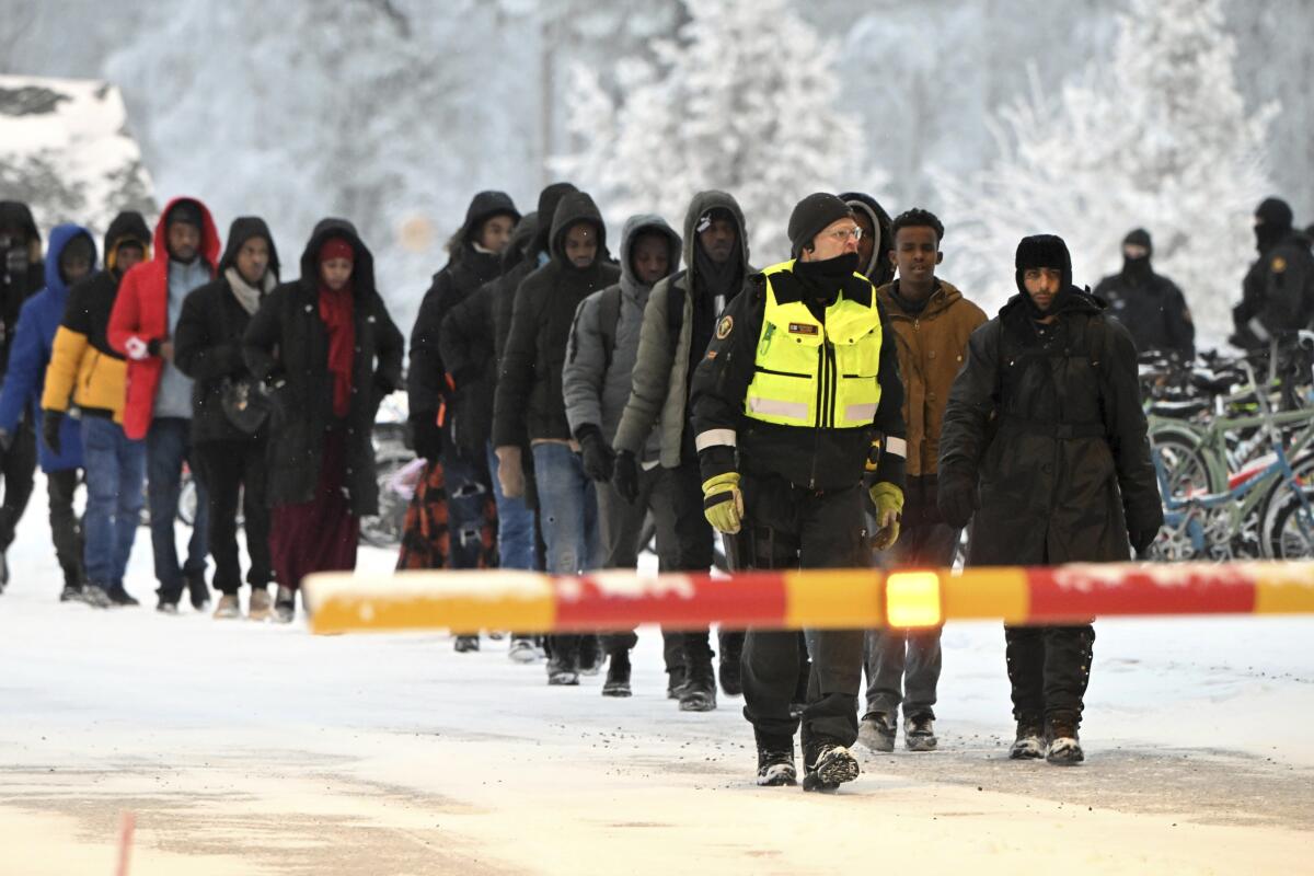 Finnish border guards escort migrants.
