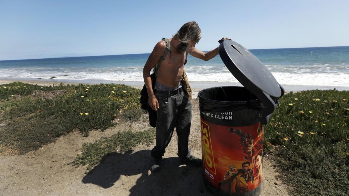 Jack Brown, 37, looks through trashcans on the beach May 15 in Malibu. He is homeless and was looking for food.