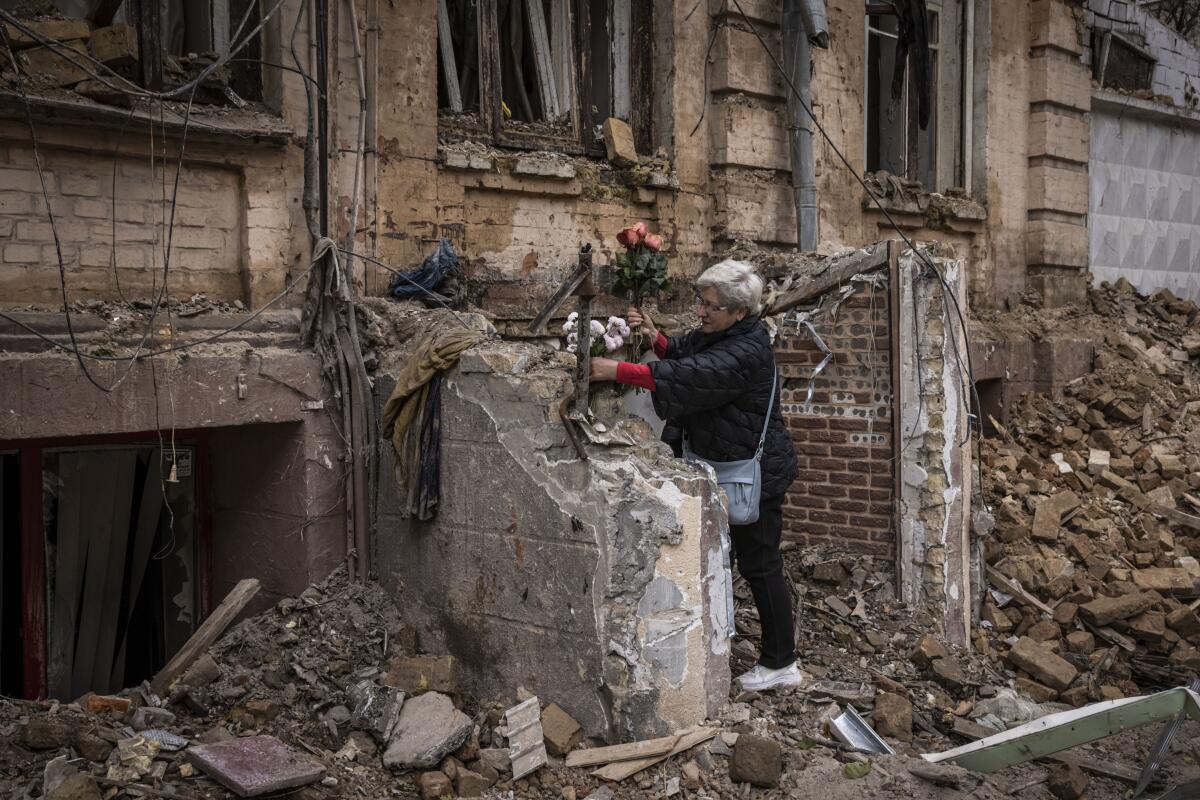 A woman arranges flowers outside a house hit by a Russian drone.