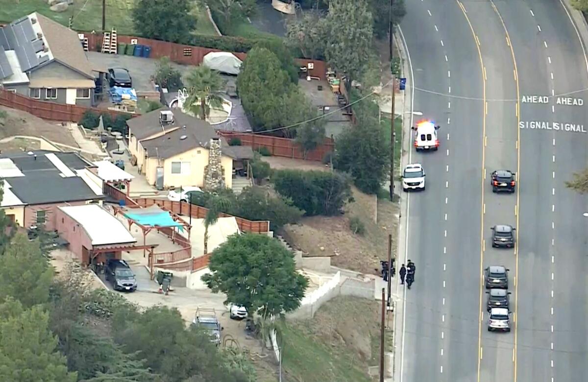 An aerial view shows police cars stopped in the road outside homes.
