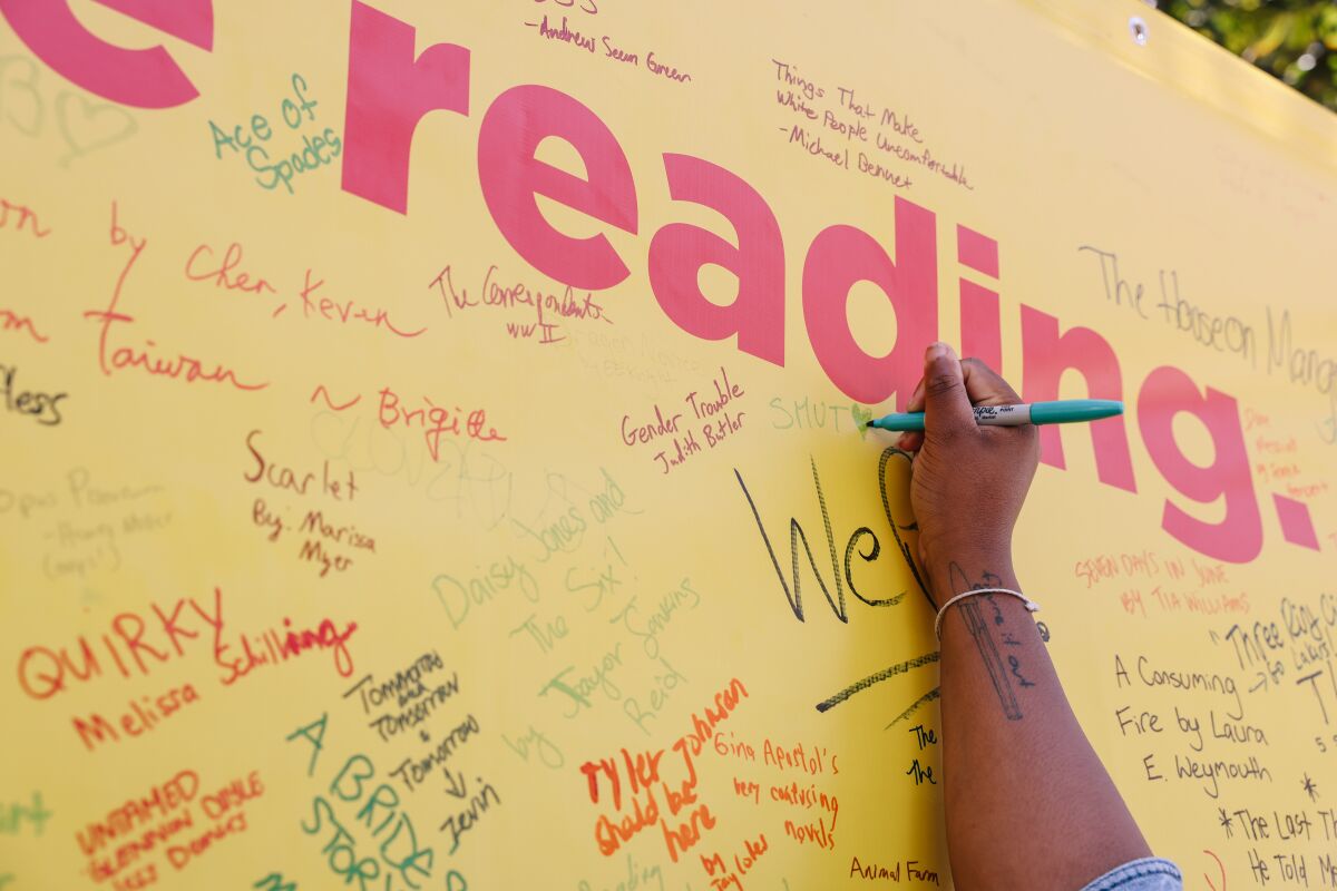 People fill a board with the names of books they love or are currently reading.