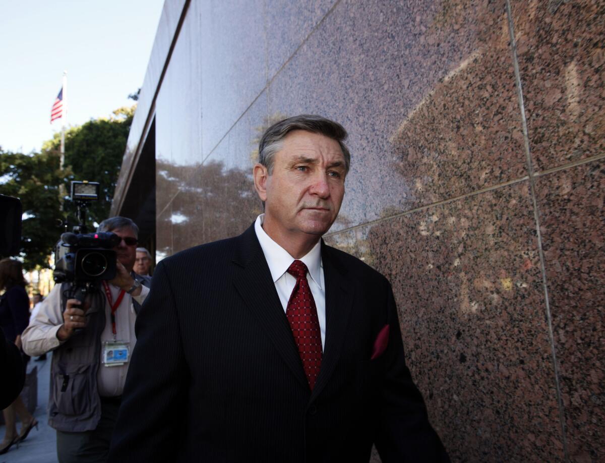 A white man in suit and tie is followed by a videographer