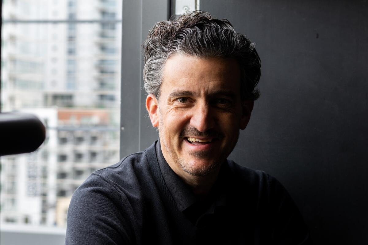 Carlos de la Mora smiles in a close-up head and shoulders photograph.