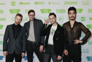 Four men pose on a red carpet before a benefit concert