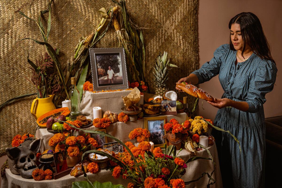 A woman arranges her home's ofrenda with vibrant marigolds, candles and mementos