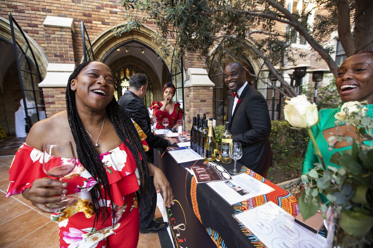 Tuanni Price, left, the owner of Zuri Wines, shares a laugh with Chadwick Spell, second from right, the chief operating officer of Wachira Wines, and Esther Nabwire, right, during a fundraising event at Loyola High School called Raise the Barr, where Price provided wine tastings.