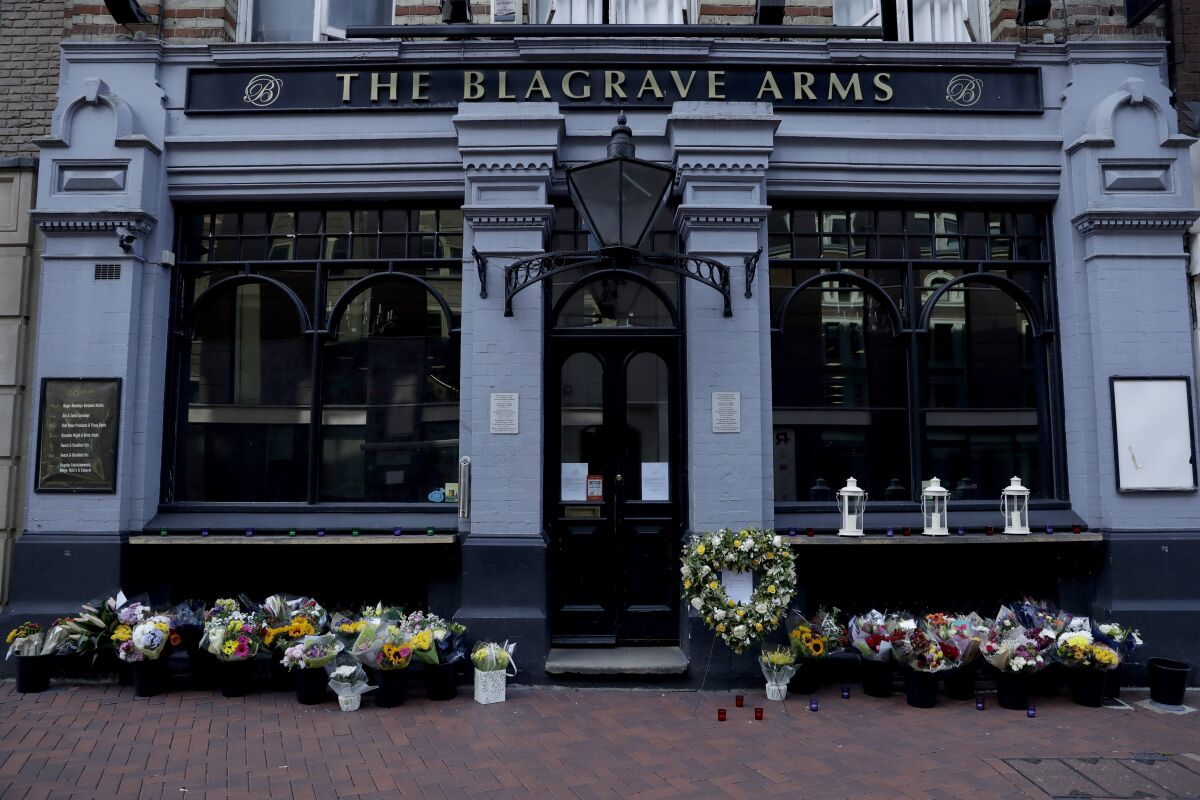 FILE - In this Tuesday, June 23, 2020 file photo, flowers are placed outside the Blagrave Arms pub near the scene of a fatal multiple stabbing attack in Forbury Gardens park, in Reading, England. A 26-year-old Libyan man pleaded guilty to murder on Wednesday, Nov. 11 for stabbing three men to death as they sat in an English city park. Khairi Saadallah admitted three counts of murder and three of attempted murder for the June 20 attack in Reading, 40 miles (64 kilometers) west of London. Friends James Furlong, David Wails and Joseph Ritchie-Bennett were enjoying a warm Saturday evening in the town’s Forbury Gardens park when they were stabbed. (AP Photo/Matt Dunham, file)