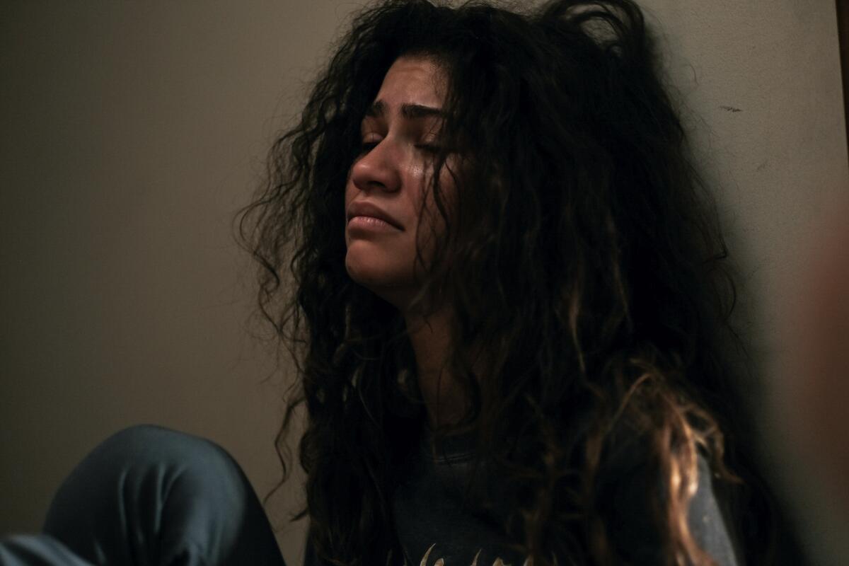 A young woman looking distraught leans against a wall in a scene from "Euphoria."