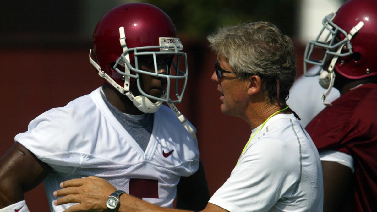 USC running back Reggie Bush speaks with Coach Pete Carroll during a practice session in 2005. NCAA sanctions imposed on USC's sports programs end Tuesday.