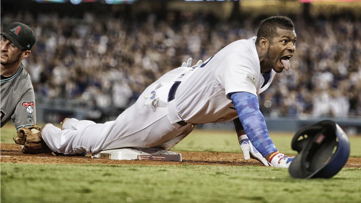 Dodgers right fielder Yasiel Puig exults after sliding into third past the tag of DBacks third baseman Adam Rosales for a seventh inning triple in game one of the NLDS at Dodger Stadium.