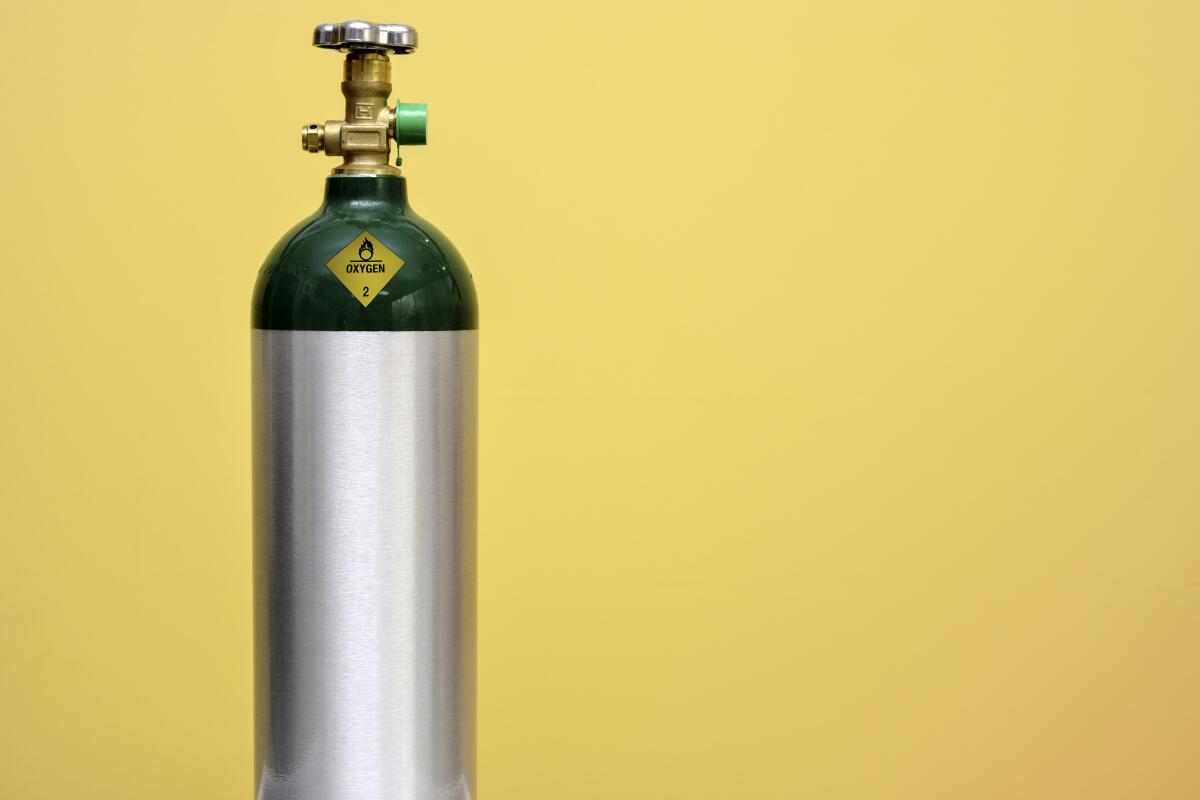 Green and silver medical oxygen tank isolated on yellow background