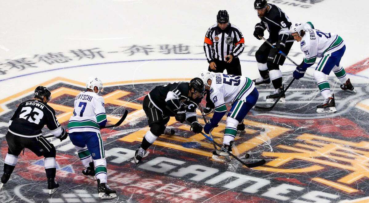 The Kings and Canucks fight for the puck during a preseason game at Mercedes-Benz Arena in Shanghai on Sept. 21, 2017.