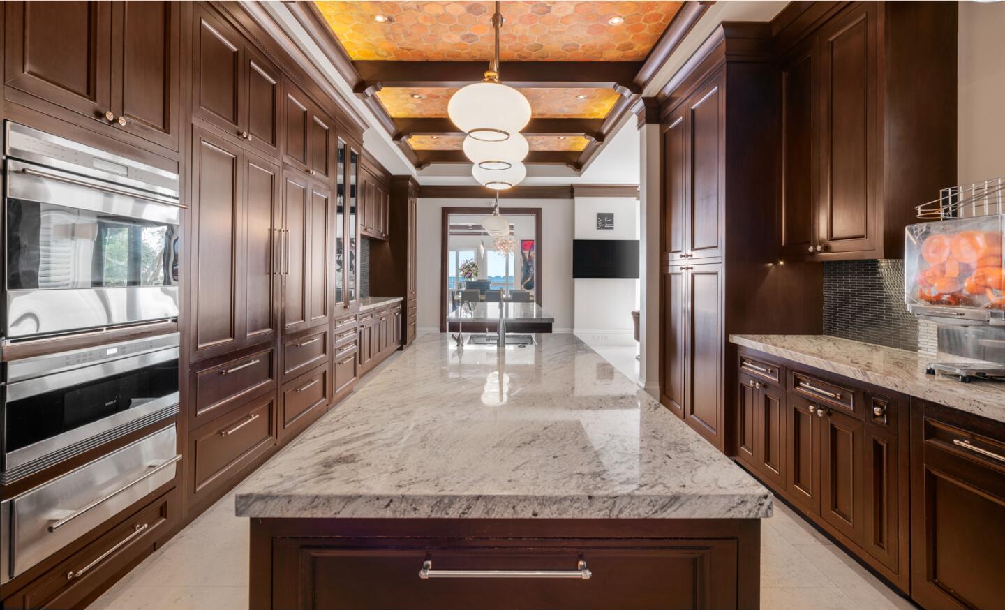 A long center island in the kitchen with a marble counter top.