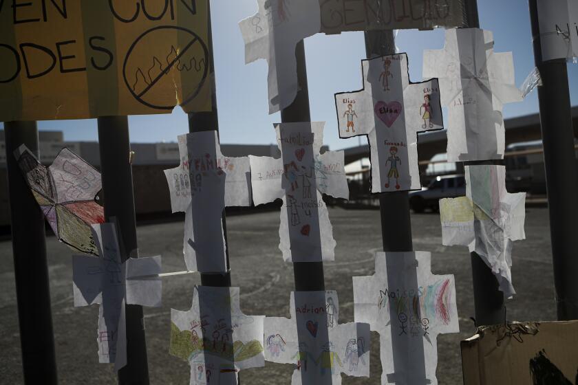 Cruces de papel con los nombres de los migrantes que murieron en el incendio del mes pasado están pegadas en una valla del centro de detención de migrantes en el que más de tres docenas de personas murieron por el fuego que se inició en una de las celdas, en Ciudad Juárez, México, el jueves 20 de abril de 2023. (AP Foto/Christian Chávez)