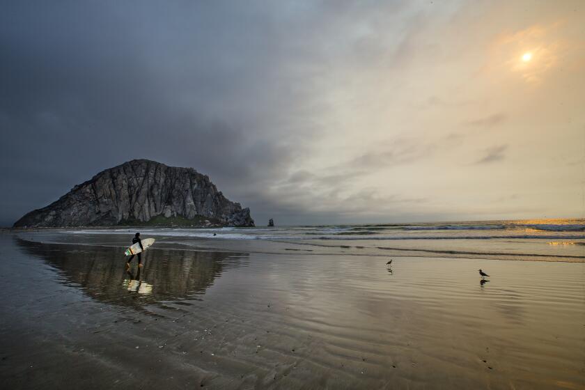 MORRO BAY, CA -- WEDNESDAY, AUGUST 3, 2016: A surfer and Morro Rock are reflected in the water at low tide as the sun goes down with ash visible from a forest fire in Morro Bay. Steve Lopez takes a California coastal tour marking the 40th anniversary of the Coastal Act in California, CA, on Aug. 3, 2016. (Allen J. Schaben / Los Angeles Times)