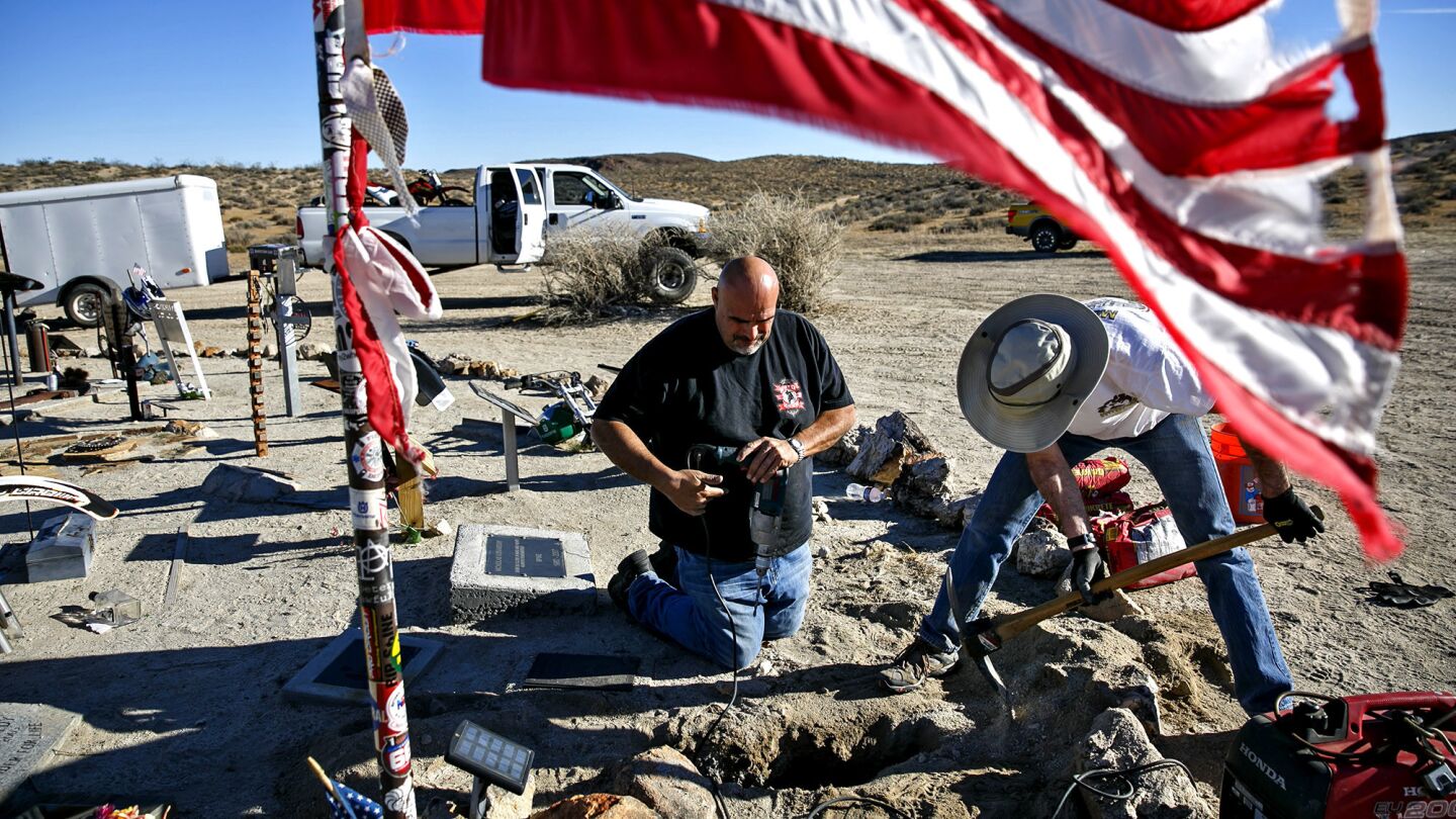 Fernando Garcia, left, and Stephen Marks install a motorcycle memorial for the late William Cory Tuchscher at the Husky Monument near Randsburg, Calif.