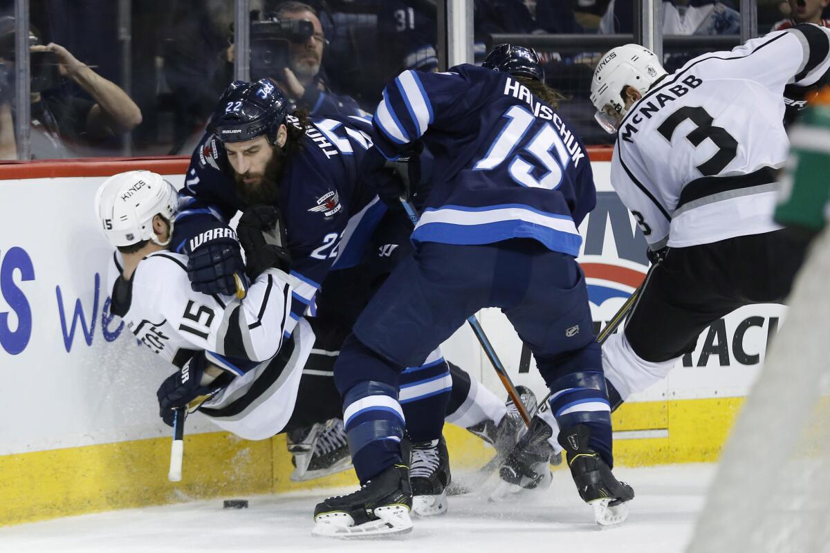 Jets right wing Chris Thorburn (22) takes down Kings left wing Andy Andreoff (15) as Jets' Matt Halischuk (15) and Kings' Brayden McNabb (3) battle for the loose puck during the second period.