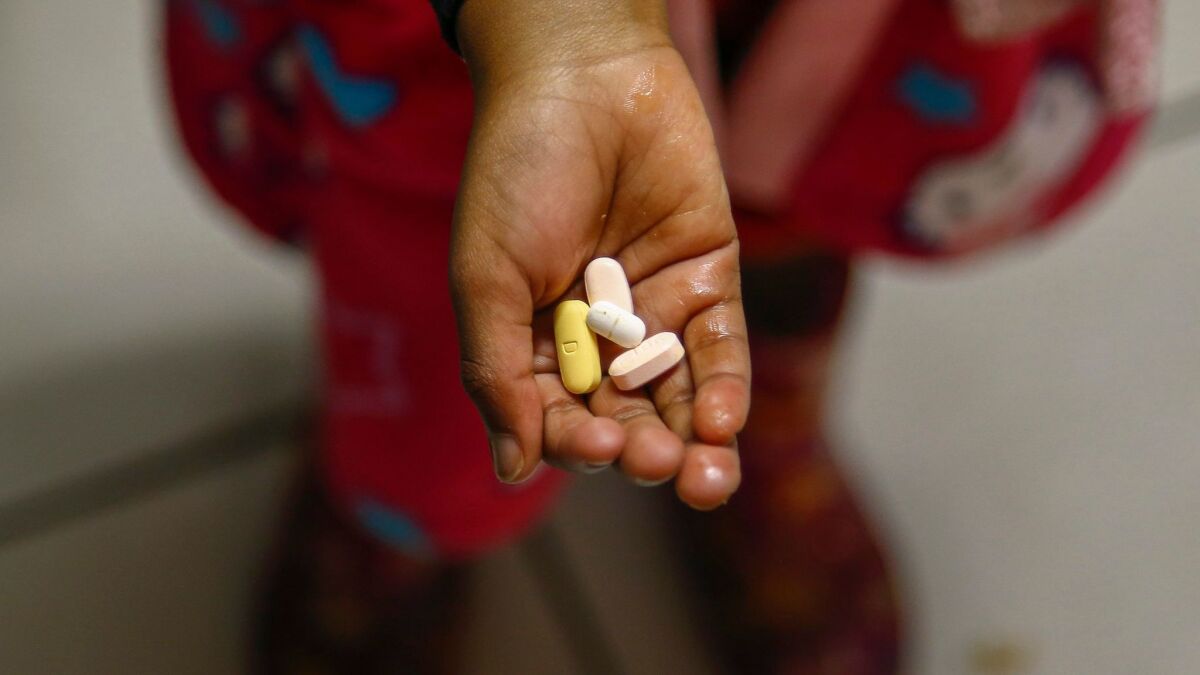 A child holds antiretroviral drugs she takes daily for HIV.