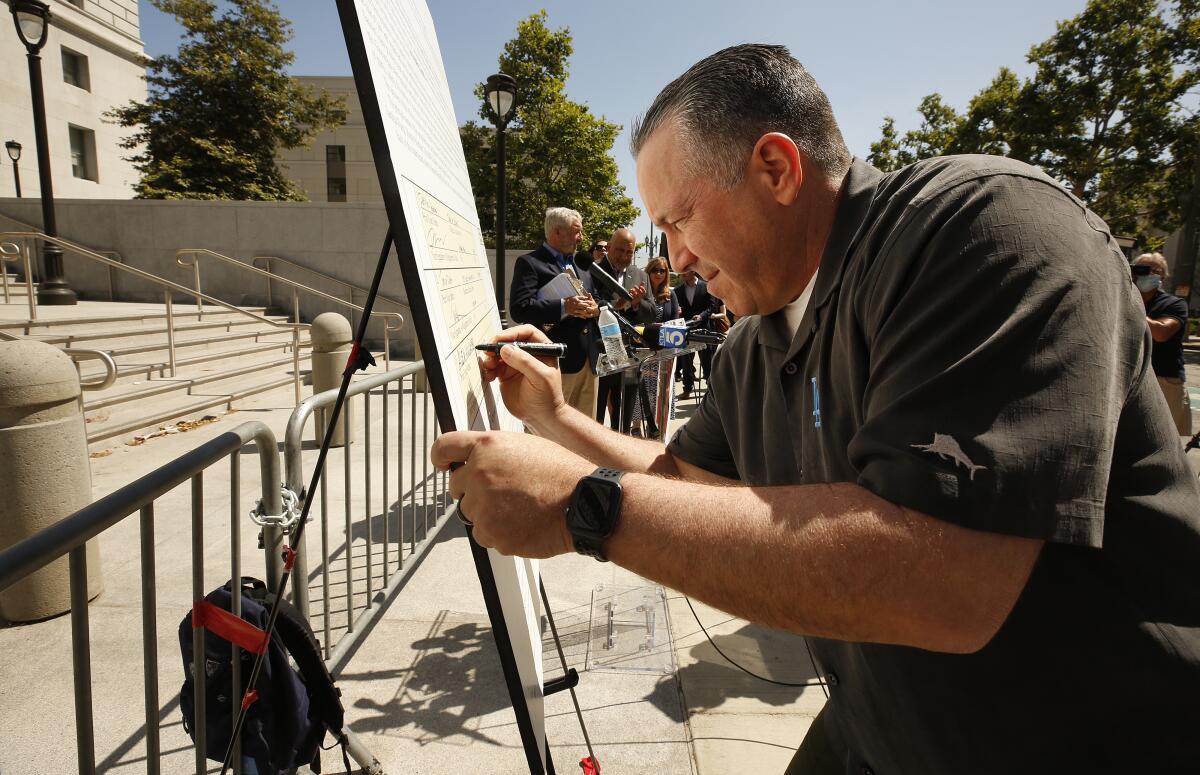 Los Angeles County Sheriff Alex Villanueva signs a petition to recall Dist. Atty. George Gascón in downtown L.A. on May 26.