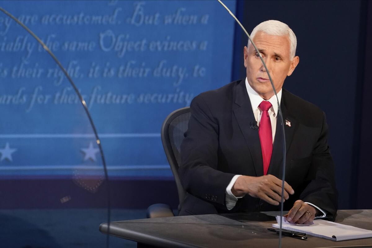 Vice President Mike Pence, seated, speaks through a plexiglass barrier at the debate. 