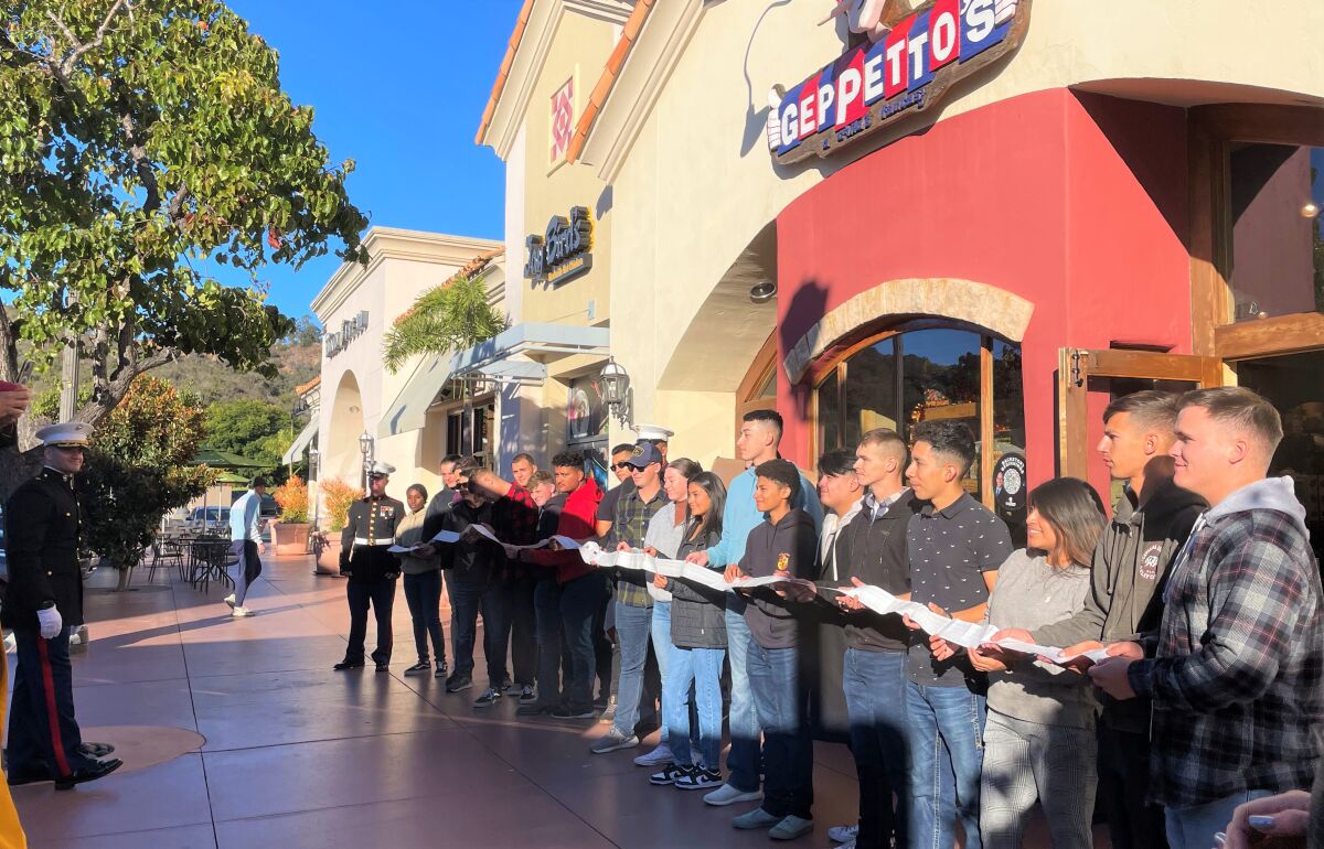 The receipt for $100,700 of toys is stretched out by those at Geppetto's in Carlsbad who loaded the Toys for Tots trucks.