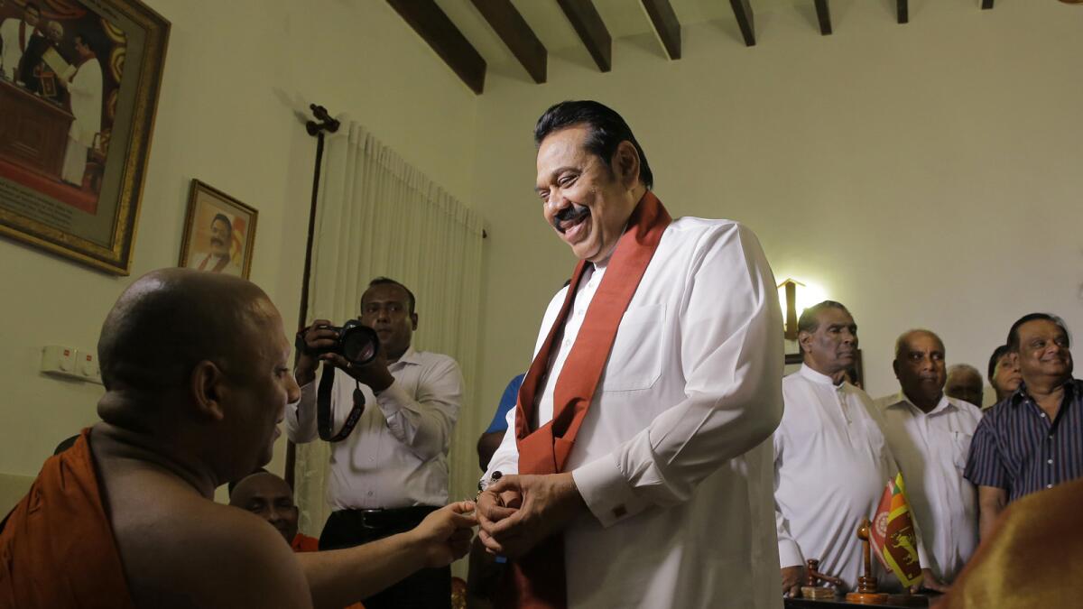 Prime Minister Mahinda Rajapaksa speaks with a Buddhist monk Saturday after signing his resignation letter at his Colombo home.