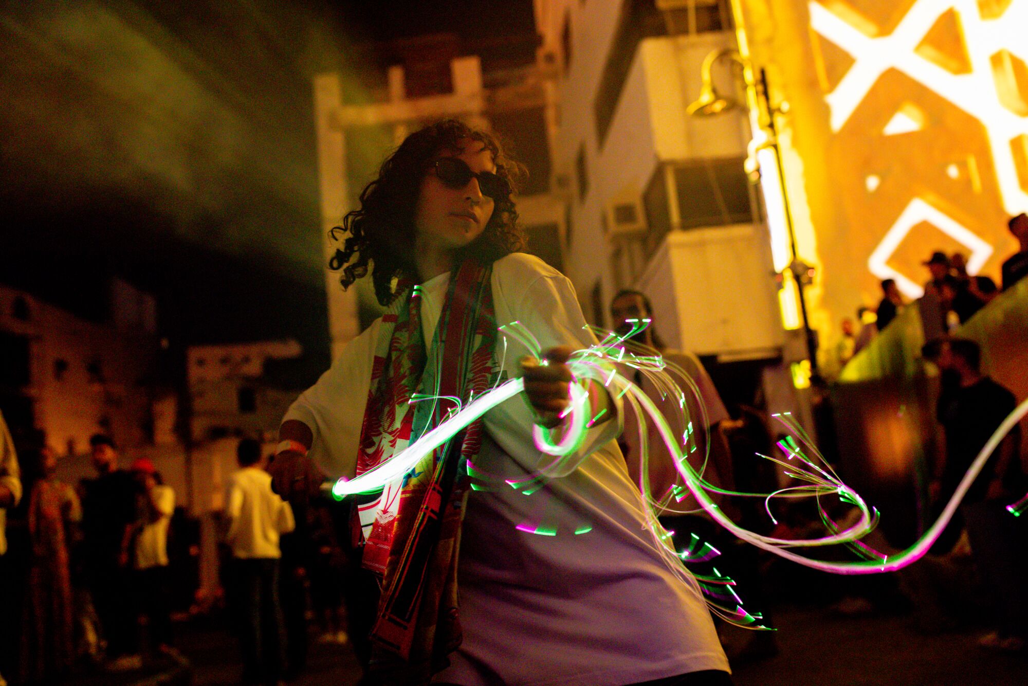 Woman dancing at a rave while holding glowing lights at night.