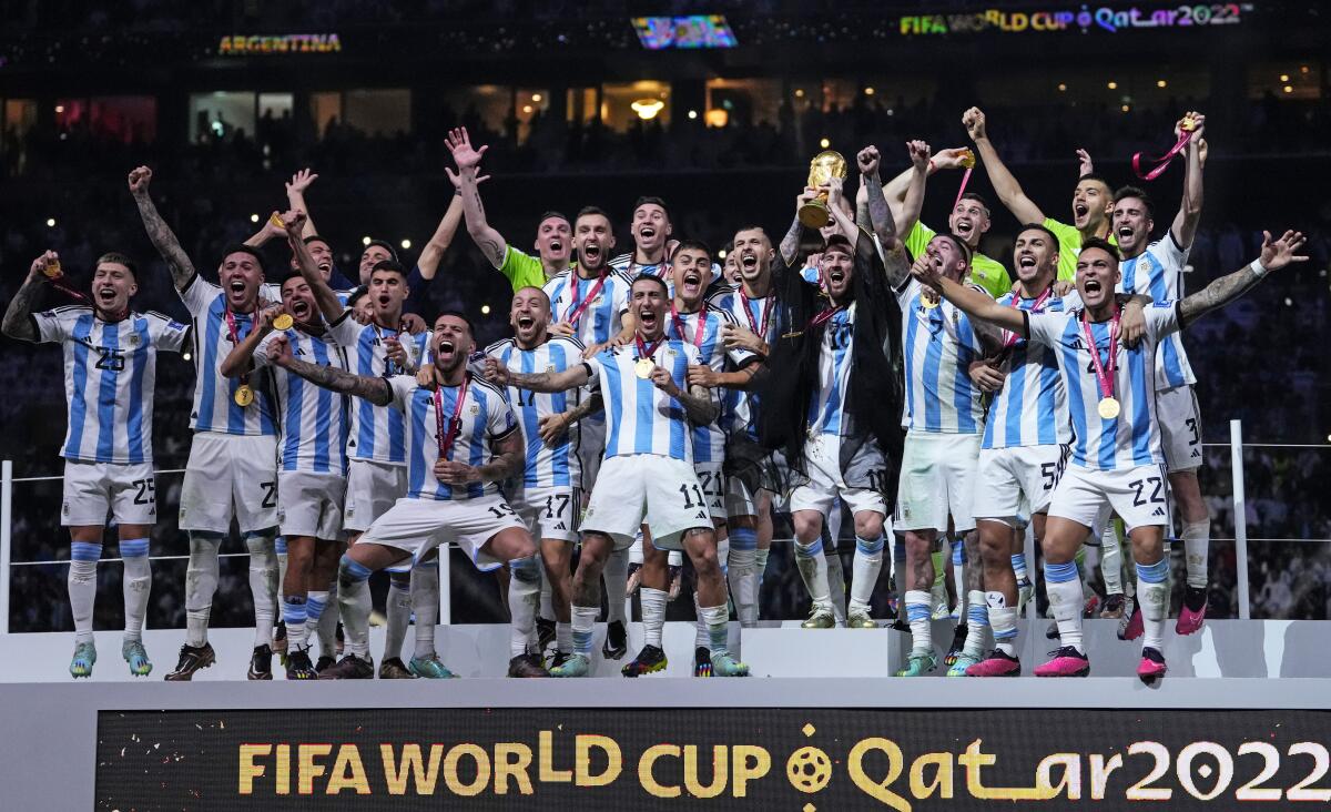 Argentina's Lionel Messi holds up the trophy in front of his teammates after winning the World Cup