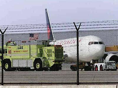 An Air Canada jet sits at the far West end of the runways at LAX surrounded by emergency vehicles