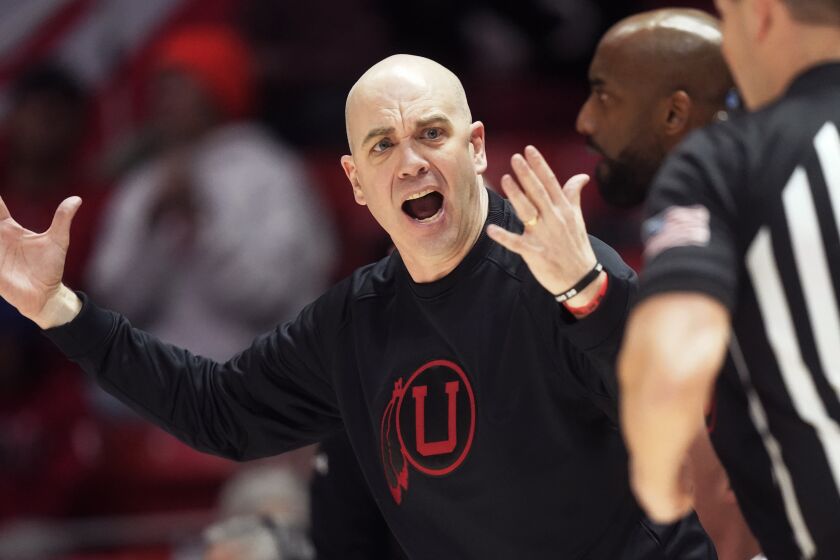 Utah head coach Craig Smith, left, argues with a referee during the second half of an NCAA college basketball game against Stanford, Thursday, Feb. 2, 2023, in Salt Lake City. (AP Photo/Rick Bowmer)