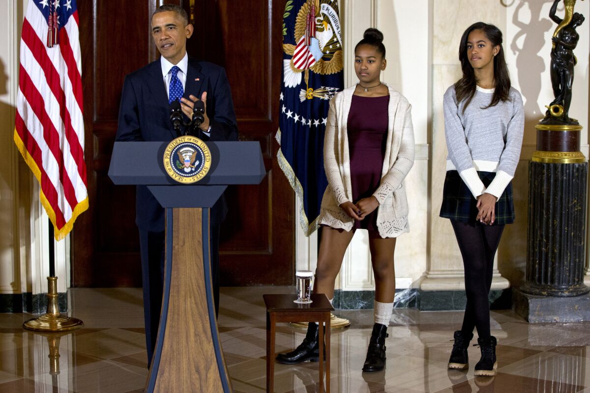 President Barack Obama, joined by his miniskirt-clad daughters Malia, right, and Sasha, center, speaks during the presidential turkey pardoning ceremony, an annual Thanksgiving tradition.