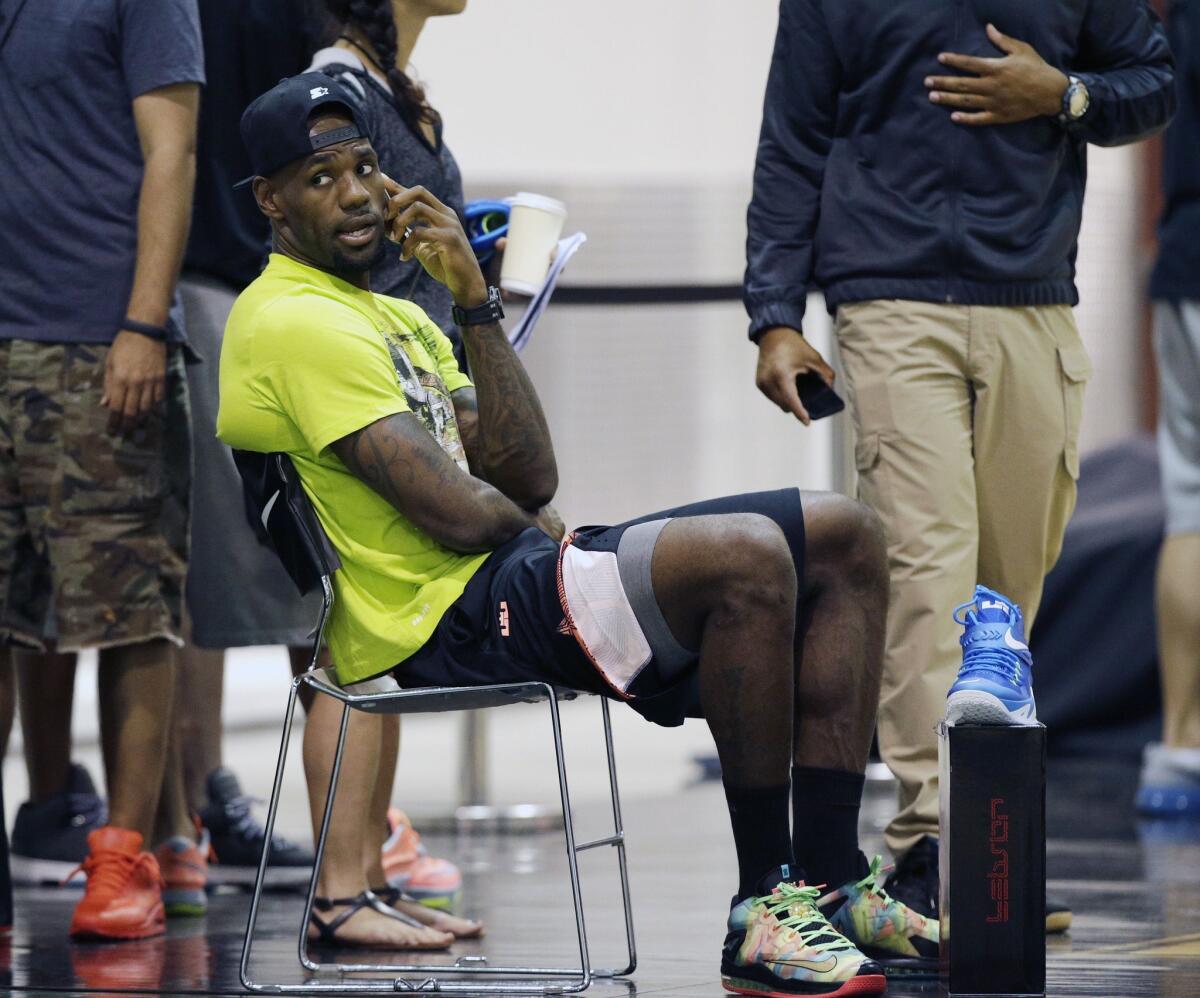 LeBron James talks on a phone Thursday during the LeBron James Skills Academy in Las Vegas. James and Carmelo Anthony, the top two free agents of the offseason, haven't announced which teams they'll be playing for next season.