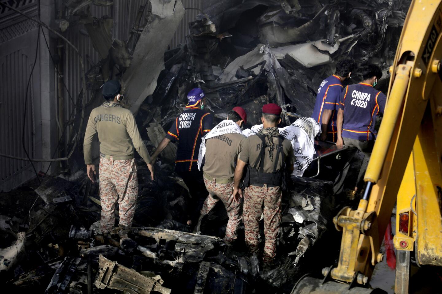 Emergency workers retrieve a body from the wreckage of a Pakistani airliner that crashed Friday in a neighborhood in Karachi.