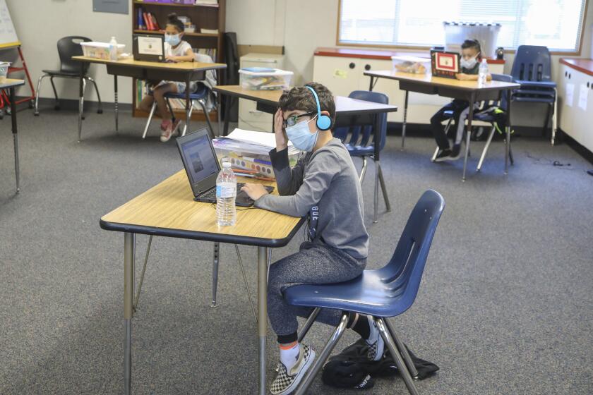 Steven Gortani, 6, and other children (background) work on their laptops at Chase Avenue Elementary School during the Cajon Valley Union School District's Emergency Child Care Program on May 5, 2020 in El Cajon, California. The district is offering free child care to essential workers.