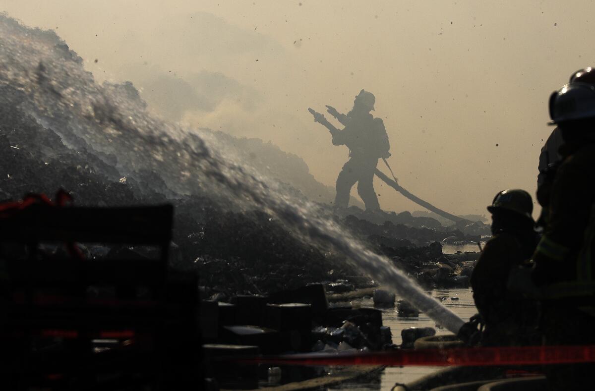 Firefighters spray hoses amid smoke in a warehouse fire