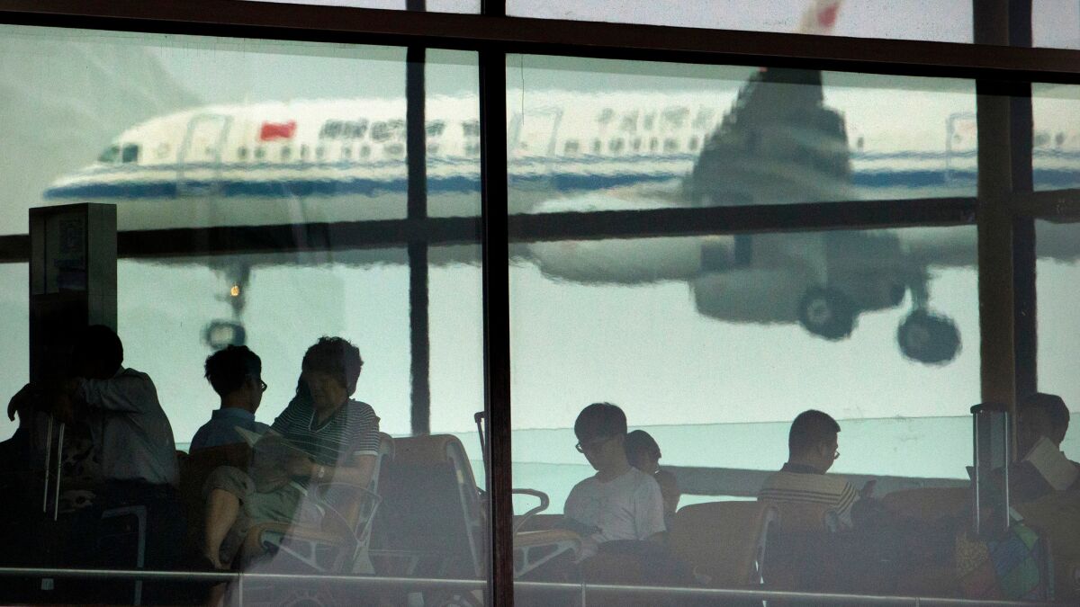Passengers at Beijing Capital International Airport sit after police detained a man over an attack on an airline check-in clerk that left her lying in a pool of blood.