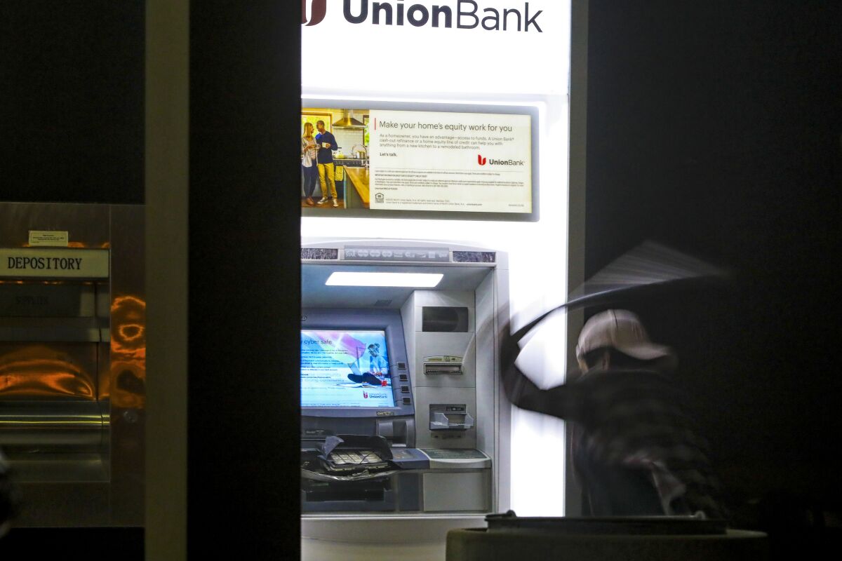 Protestors use a baseball bat to destroy the ATM at the Union Bank in La Mesa.