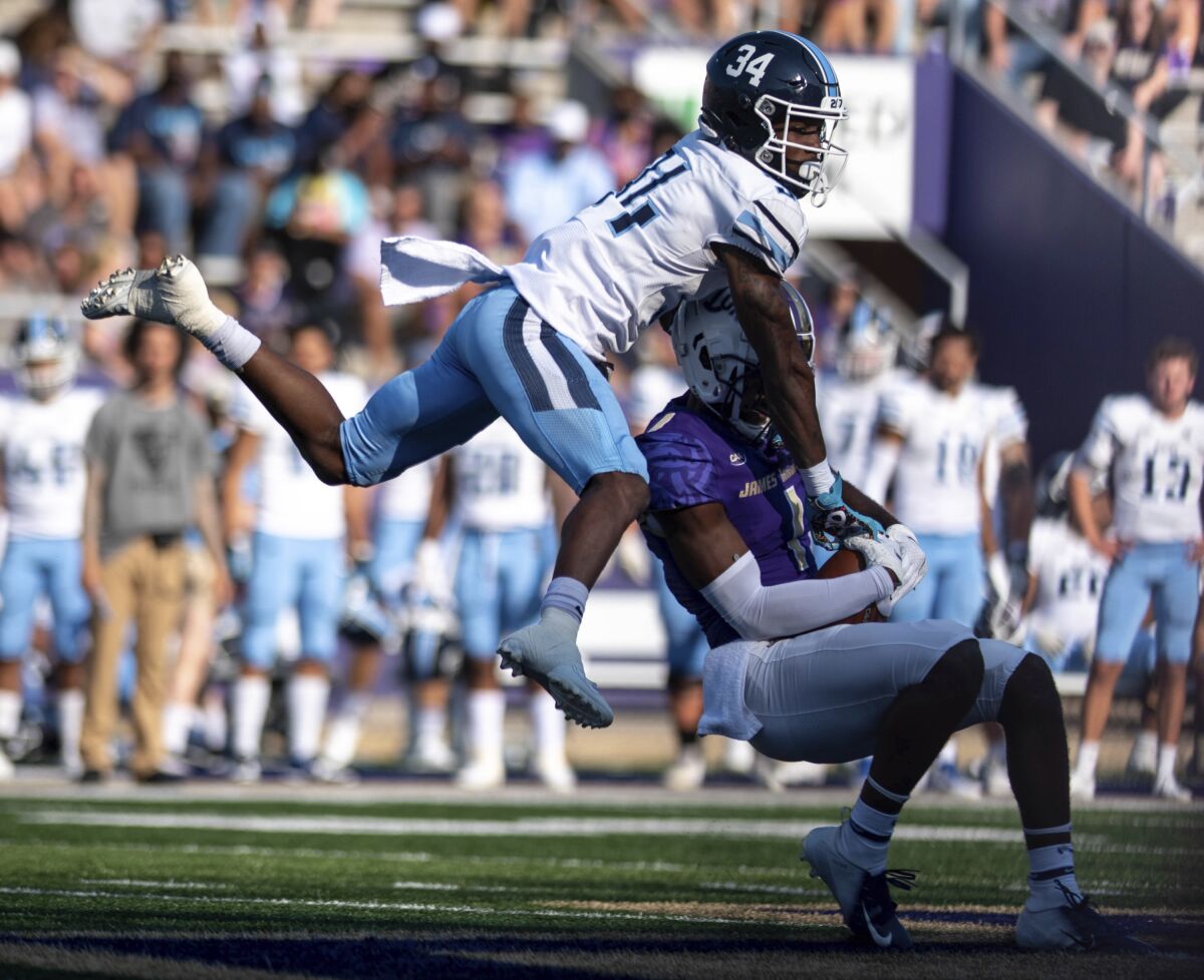 Maine defensive back Kolubah Pewee Jr. (34) leaps while defending against James Madison wide receiver Scott Bracey (1) during the first half of an NCAA college football game in Harrisonburg, Va., Saturday, Sept. 11, 2021. (Daniel Lin/Daily News-Record via AP)