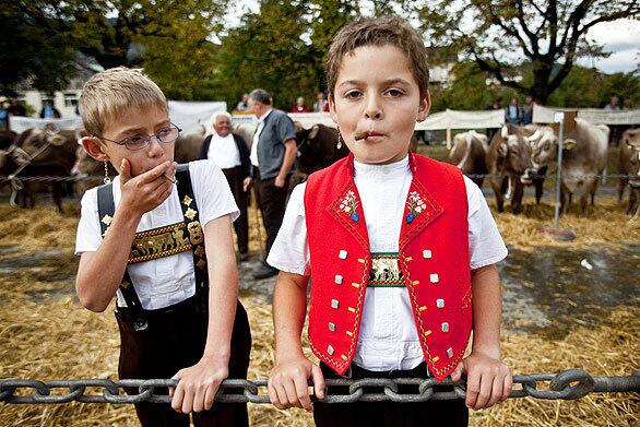 Two boys imitate adults as they visit an annual cattle market, where some farmers come in traditional costumes to sell or buy animals.